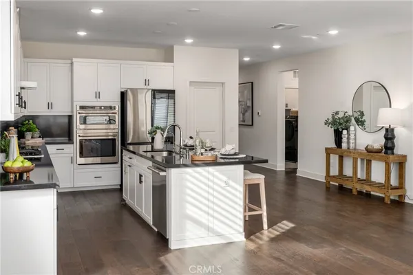 a kitchen with stainless steel appliances kitchen island granite countertop a stove a sink a refrigerator and cabinets