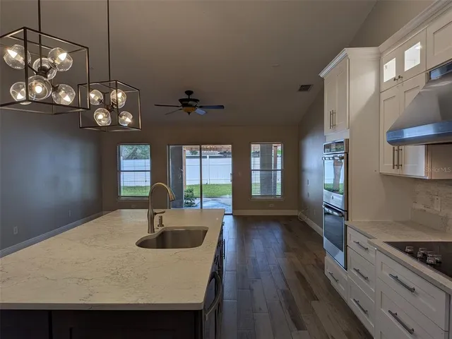 a kitchen with stainless steel appliances granite countertop a sink dishwasher a stove a dining table and chairs with wooden floor