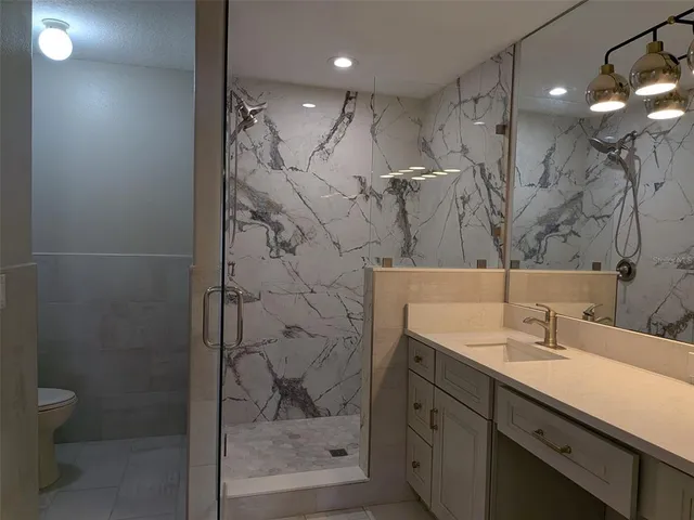 a bathroom with a shower sink vanity and toilet