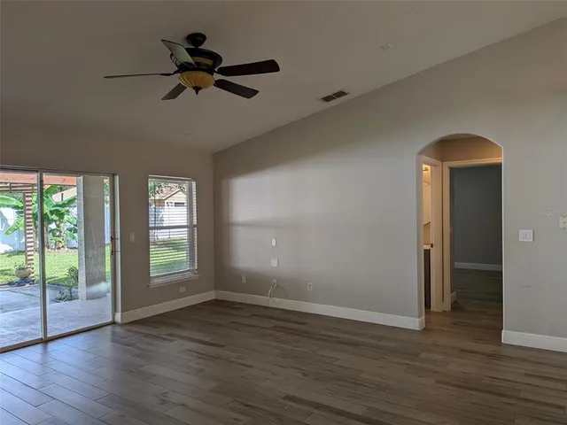 a view of empty room with wooden floor and fan