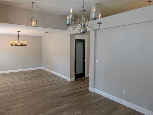 an empty room with wooden floor and chandelier