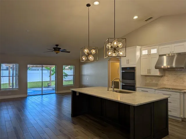 a kitchen with granite countertop stainless steel appliances a sink cabinets a stove and a center island