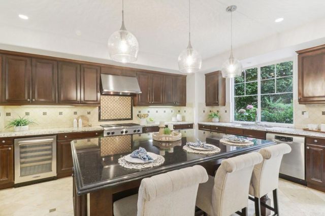 a kitchen with granite countertop a stove a sink a dining table and chairs