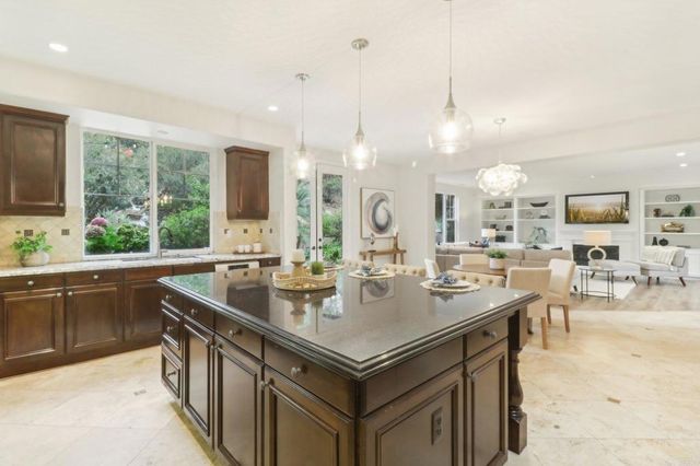 a kitchen with granite countertop a sink a counter top space and living room view