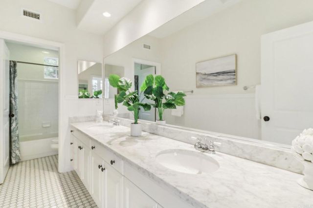 a bathroom with a granite countertop double vanity sink and a large mirror
