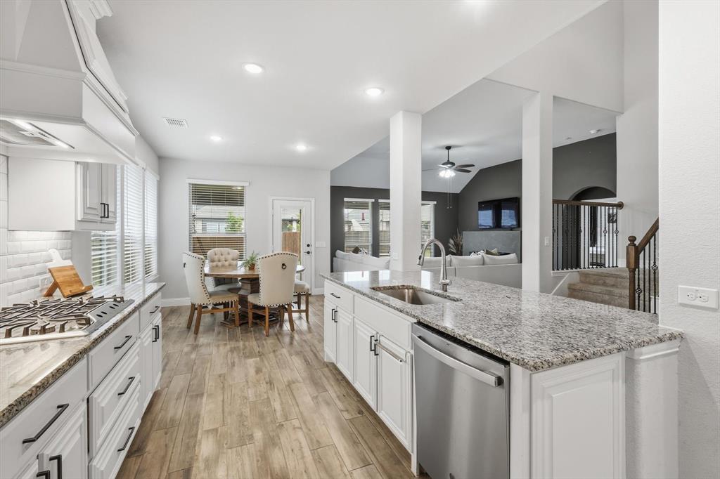 924 Timber Ridge Drive Justin, TX 76247 - Photo 13 of 32 Gourmet kitchen with granite countertops, stainless steel appliances, wood-finish flooring, white cabinetry, and recessed lighting