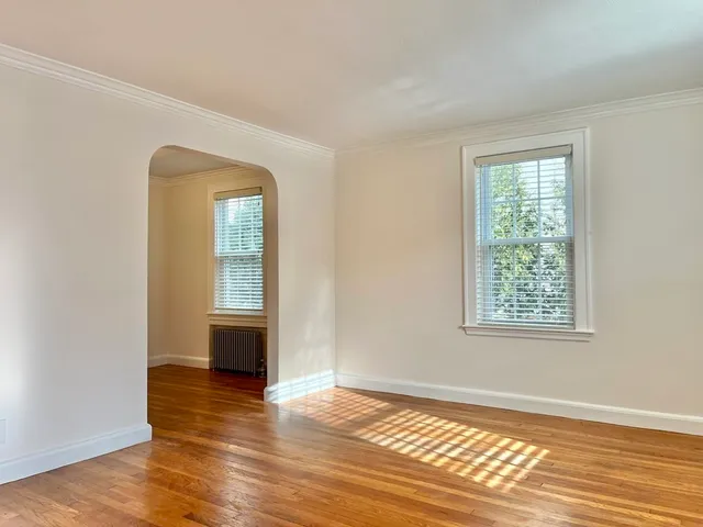 a view of an empty room with window and wooden floor
