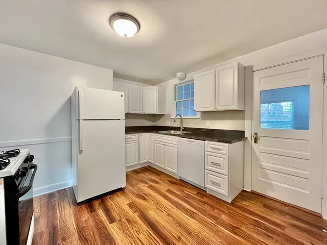 a kitchen with granite countertop white cabinets and white appliances