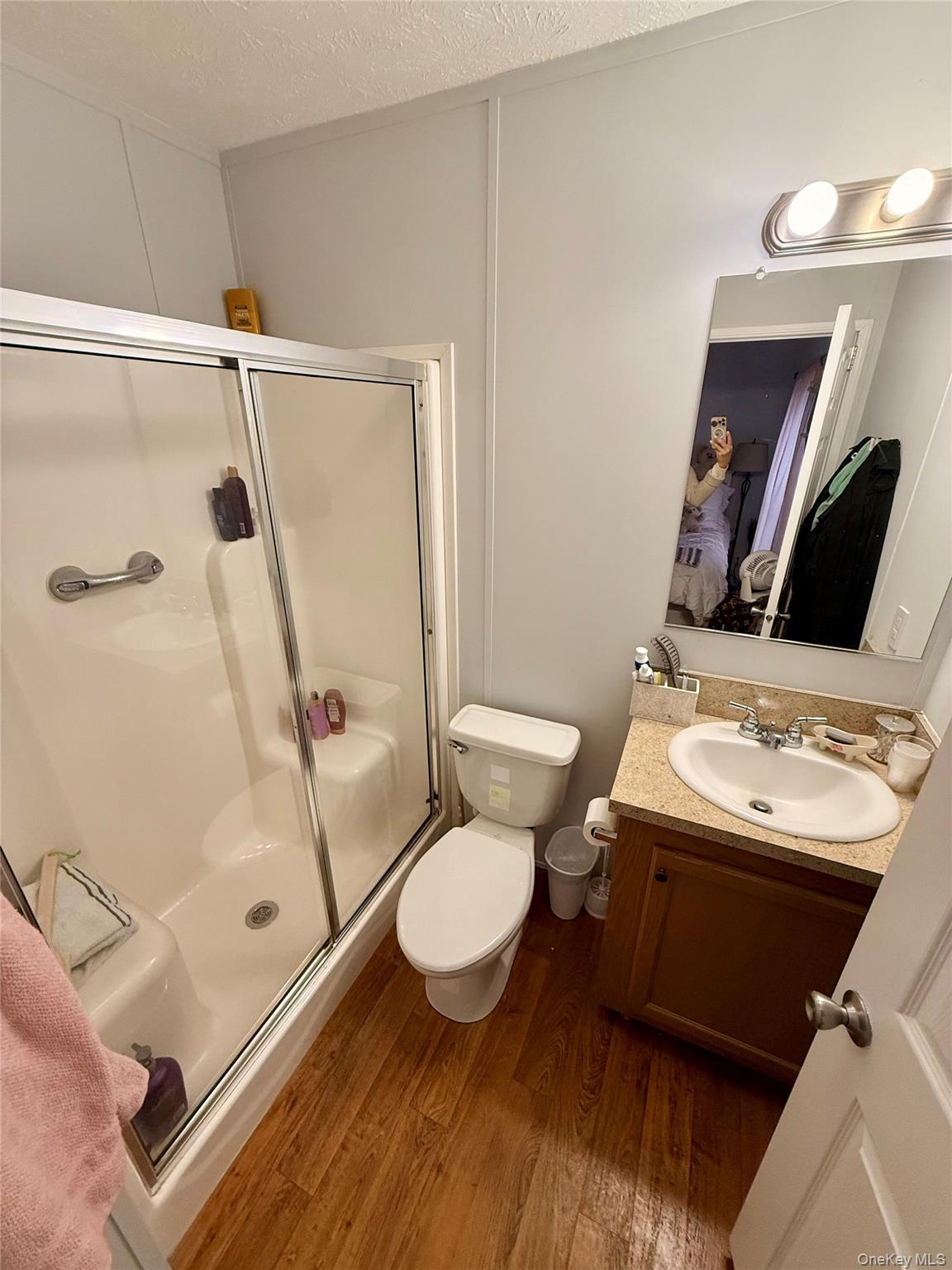 37 Hubbard Avenue, Unit 95 Riverhead, NY 11901 - Photo 11 of 14 Bathroom featuring dark wood-style flooring, ensuite bathroom, a shower stall, a textured ceiling, and vanity