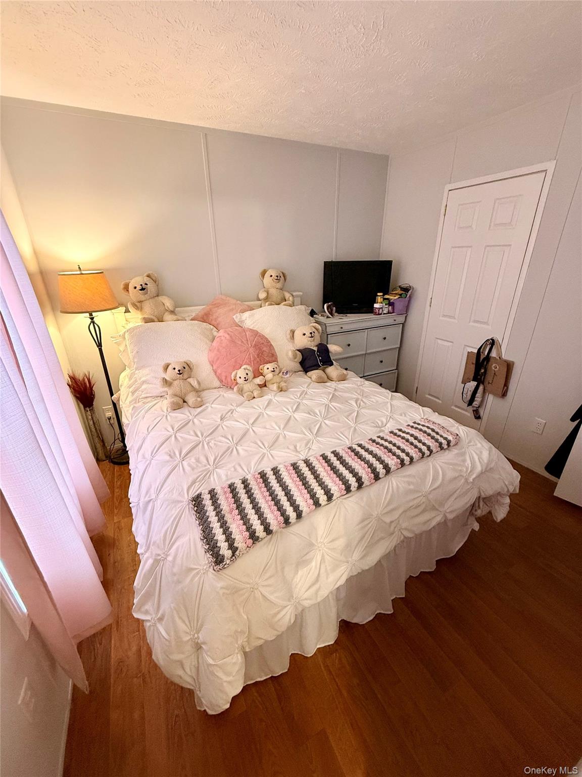 37 Hubbard Avenue, Unit 95 Riverhead, NY 11901 - Photo 10 of 14 Bedroom featuring a decorative wall, a textured ceiling, and wood finished floors