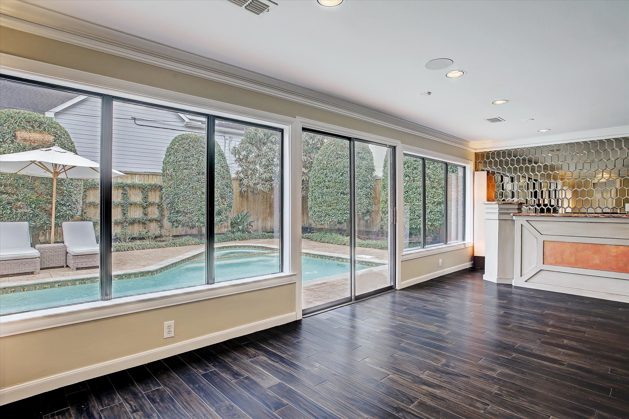 2003 Chilton Road Houston, TX 77019 - Photo 6 of 17 Look at the natual light coming in through the wall of windows and doors overlooking the pool and landscaped patio. This room makes an excellent game room with its proximity to the outdoors. A swanky oversized built-in wet bar creates an inviting living space ideal for fun and games with family and friends.