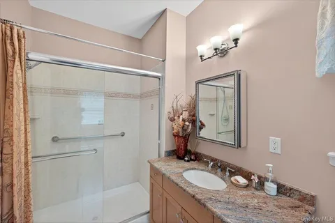 a bathroom with a granite countertop sink a mirror a vanity and a shower