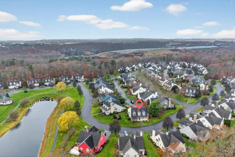 an aerial view of a house with a swimming pool lake and mountain view in back