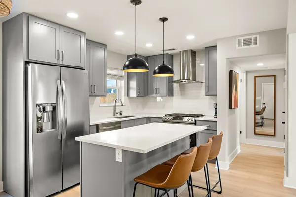 a kitchen with stainless steel appliances a refrigerator a sink a stove a dining table and chairs