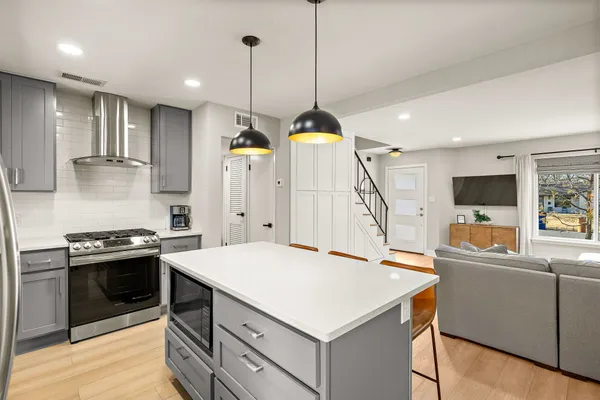 a kitchen with a stove a sink a kitchen island with wooden floor and cabinets