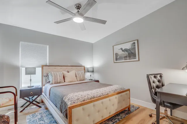 a bedroom with a bed a chair and painting on the wall