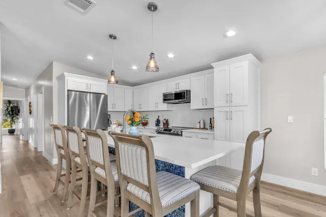 a kitchen with stainless steel appliances granite countertop a refrigerator a stove a sink a dining table and chairs