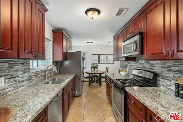 a kitchen with granite countertop a sink a counter top space appliances and cabinets