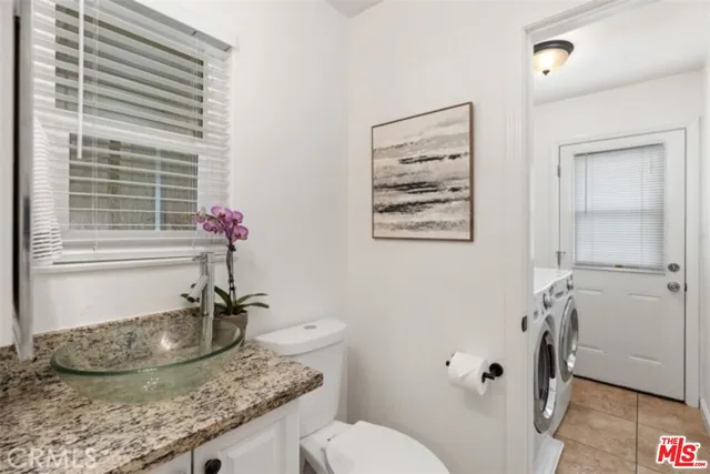a bathroom with a granite countertop sink a toilet and a window