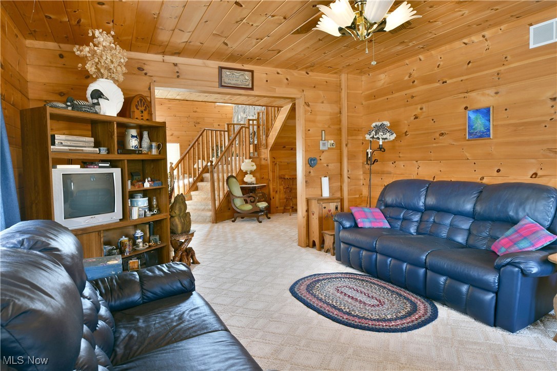 3339 Bushnell Campbell Road Fowler, OH 44418 - Photo 17 of 50 Living area featuring visible vents, light carpet, wood walls, wooden ceiling, and stairs