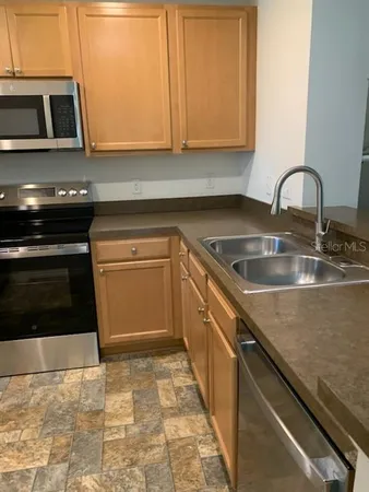 a kitchen with granite countertop a stove a sink and a microwave