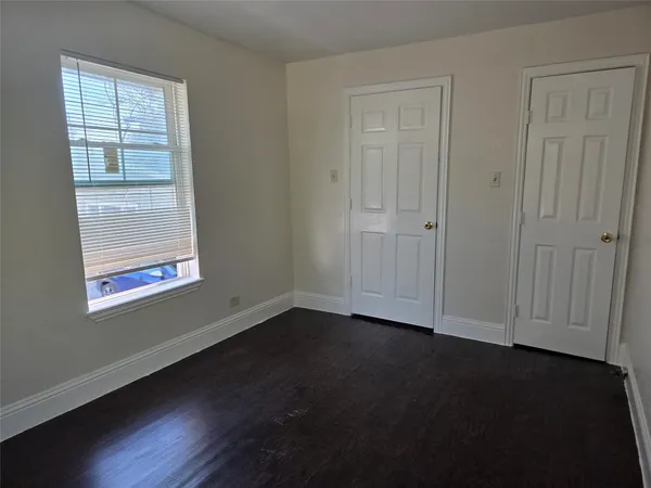 an empty room with wooden floor closet and windows