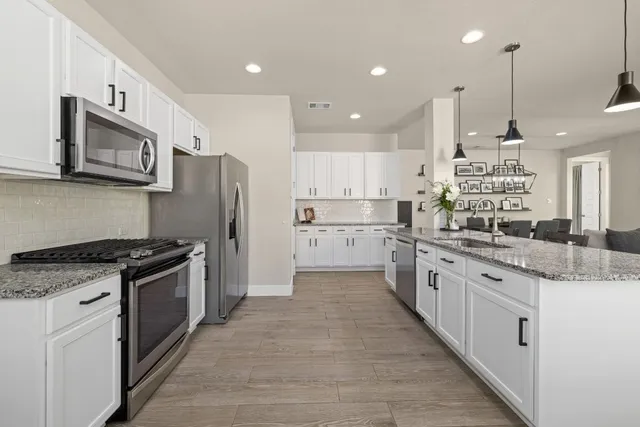 a large kitchen with stainless steel appliances granite countertop a stove a sink and a refrigerator