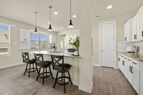 a kitchen with stainless steel appliances kitchen island granite countertop a table chairs stove a sink and a refrigerator