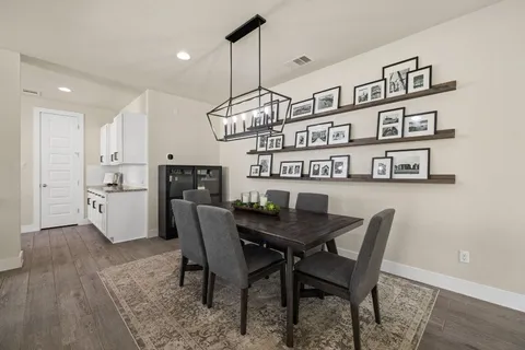 a view of a dining room and livingroom with furniture wooden floor a chandelier