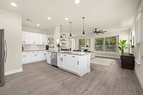 a kitchen with stainless steel appliances kitchen island wooden floors stove and white cabinets