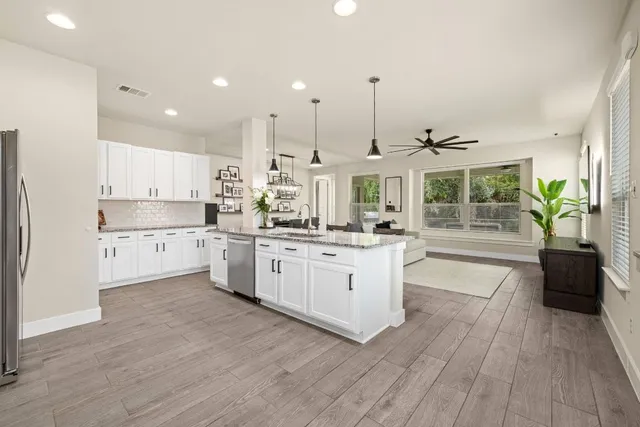a kitchen with stainless steel appliances kitchen island wooden floors stove and white cabinets