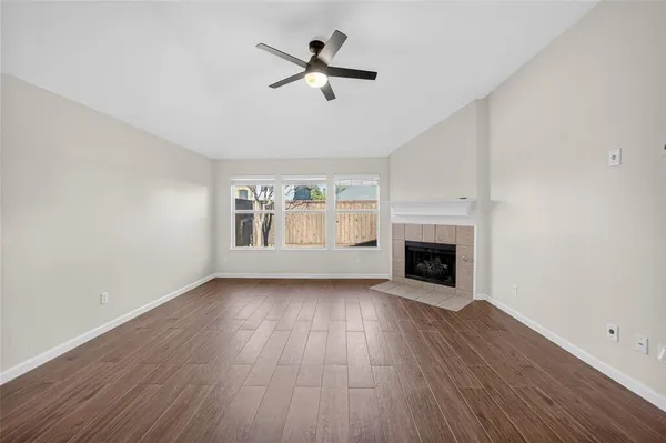 an empty room with wooden floor fireplace and windows