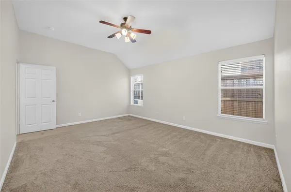 an empty room with windows and fan