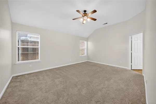 an empty room with windows and ceiling fan
