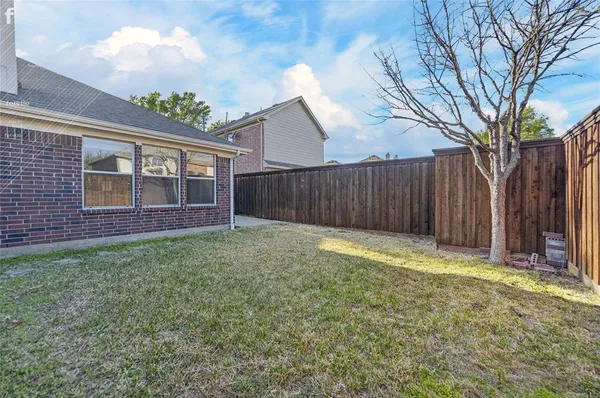 a view of a backyard with large trees and wooden fence