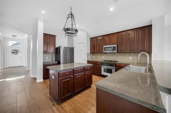 a kitchen with stainless steel appliances granite countertop a stove a sink dishwasher a refrigerator and a microwave