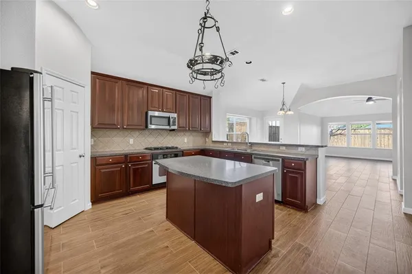 a kitchen with stainless steel appliances granite countertop a stove a sink dishwasher a refrigerator and a oven with wooden floor