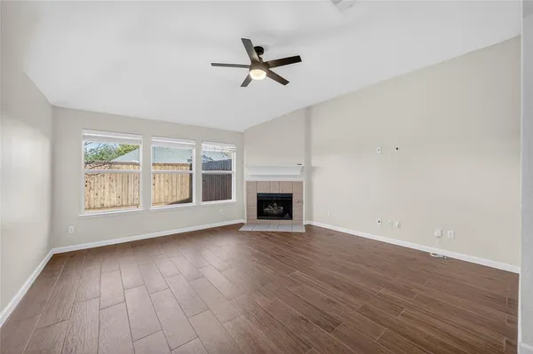 an empty room with wooden floor a ceiling fan and windows