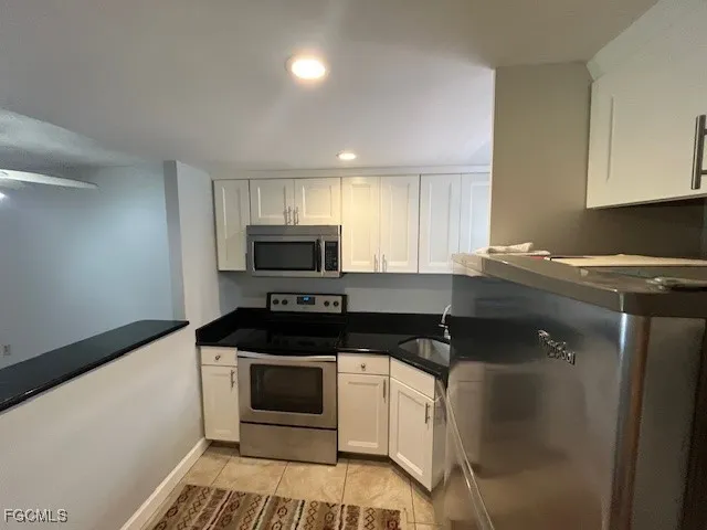 a kitchen with granite countertop a sink a stove top oven and cabinetry
