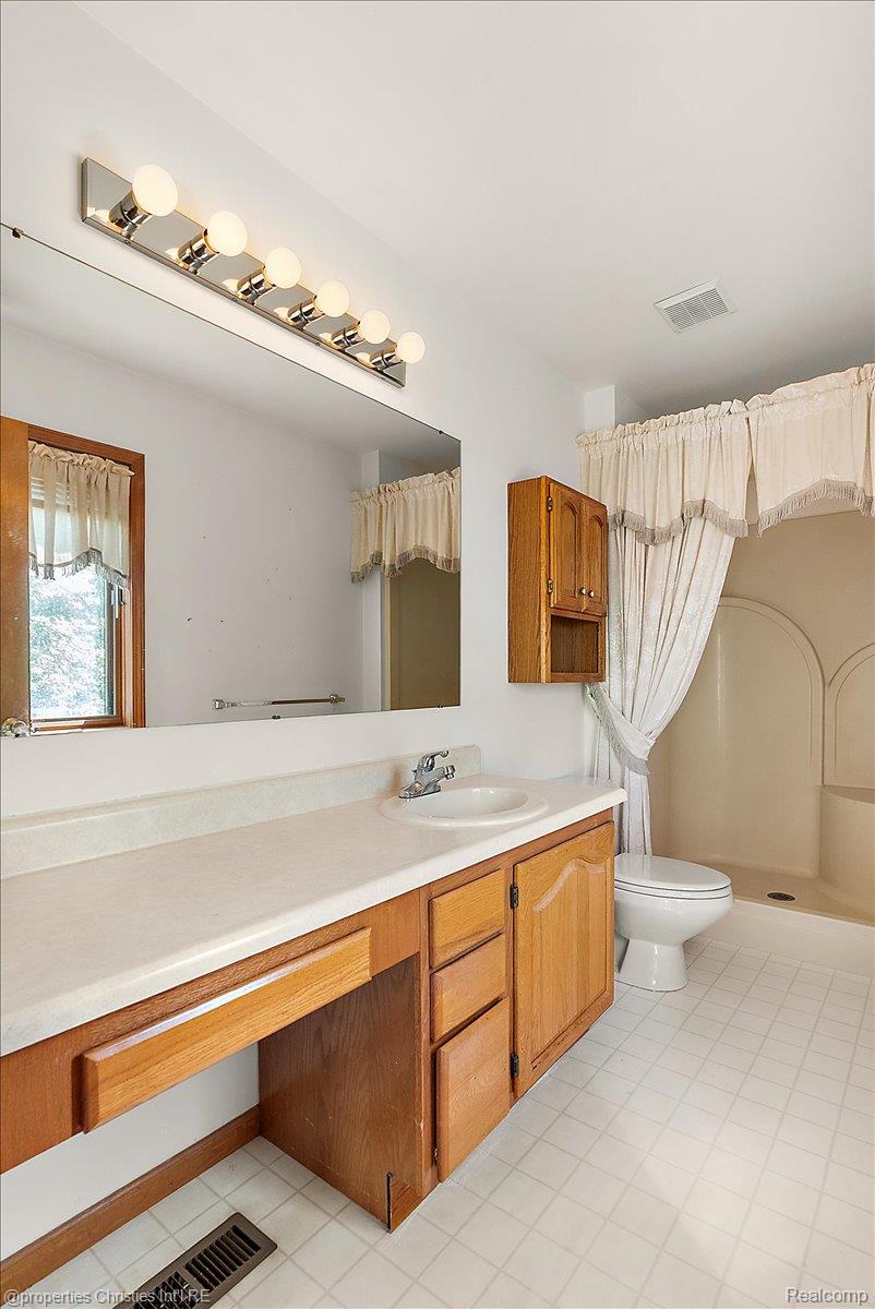 6175 Tripp Road Holly, MI 48442 - Photo 17 of 63 Bathroom vanity with a single basin sink, laminate countertop, and wood-finish cabinetry