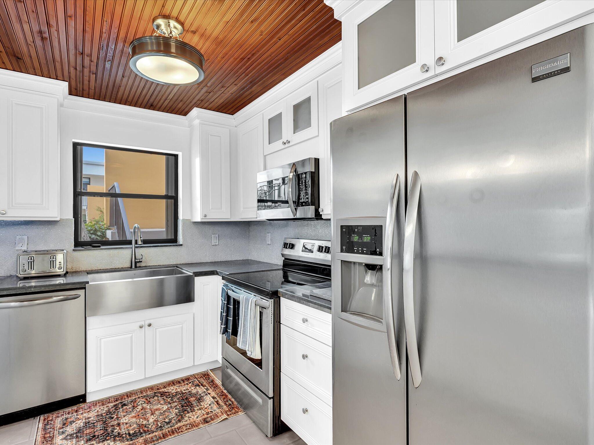 524 Osprey Drive, Unit 11B Delray Beach, FL 33444 - Photo 13 of 54 a kitchen with stainless steel appliances granite countertop a refrigerator a sink dishwasher a stove and white countertops with wooden floor