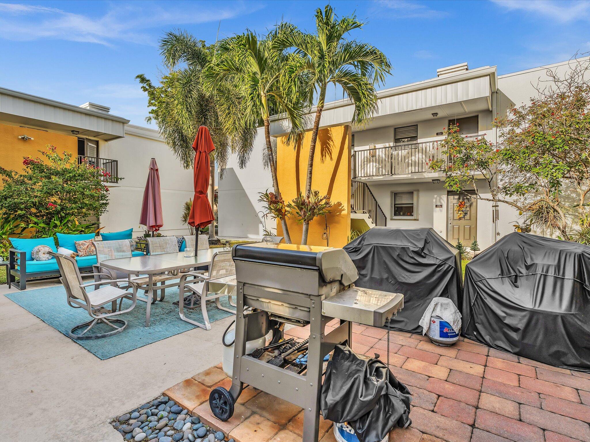 524 Osprey Drive, Unit 11B Delray Beach, FL 33444 - Photo 41 of 54 a view of a patio with table and chairs potted plants and large tree