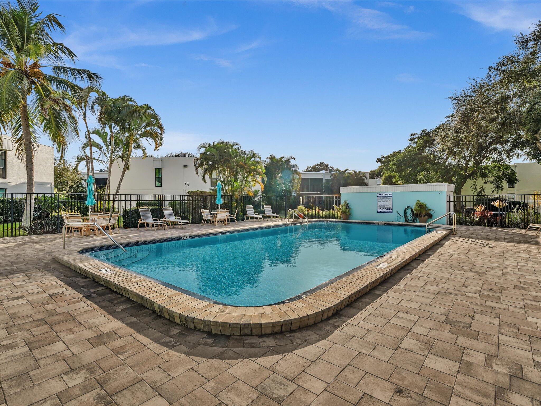 524 Osprey Drive, Unit 11B Delray Beach, FL 33444 - Photo 46 of 54 a view of a swimming pool with a yard and palm trees