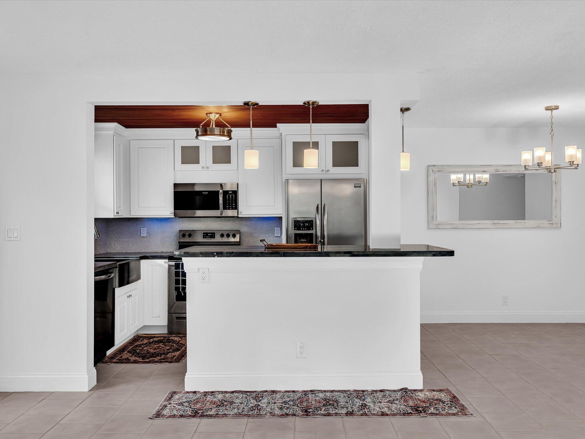 524 Osprey Drive, Unit 11B Delray Beach, FL 33444 - Photo 8 of 54 a kitchen with stainless steel appliances granite countertop a sink and a refrigerator