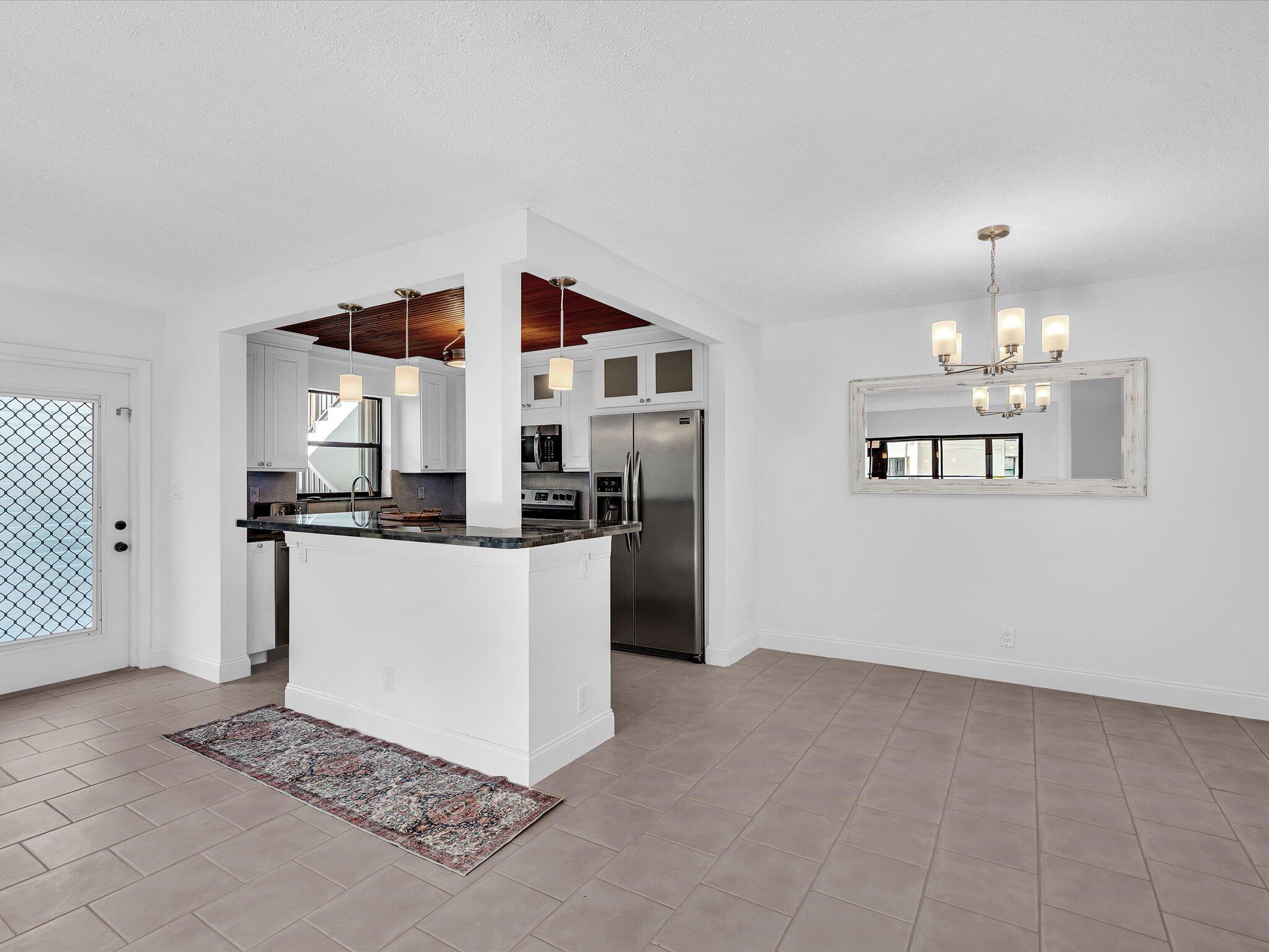 524 Osprey Drive, Unit 11B Delray Beach, FL 33444 - Photo 9 of 54 a kitchen with kitchen island granite countertop white cabinets and refrigerator