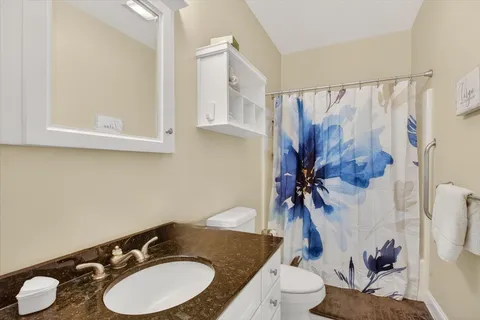 a bathroom with a granite countertop toilet sink and mirror