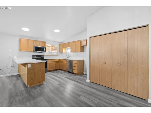 a kitchen with stainless steel appliances granite countertop a refrigerator a stove top oven a sink and dishwasher with wooden floor