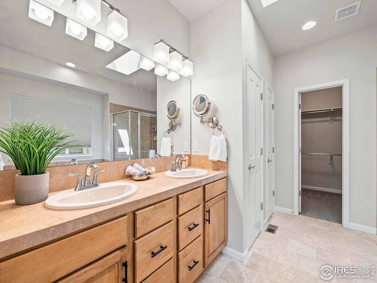 6427 Half Moon Bay Drive Windsor, CO 80550 - Photo 15 of 33 a bathroom with a sink a large mirror and a shower