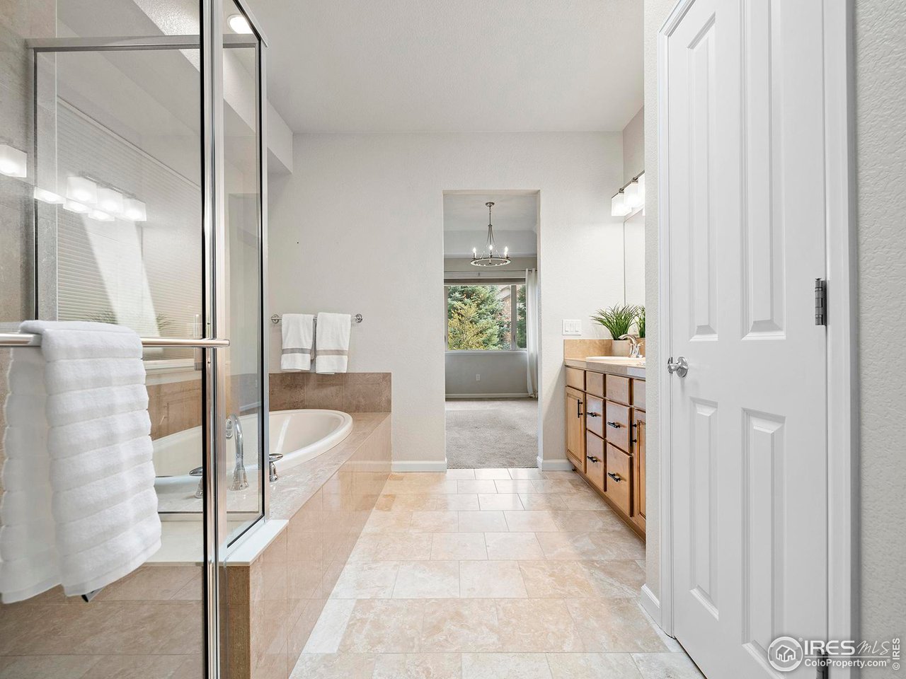 6427 Half Moon Bay Drive Windsor, CO 80550 - Photo 17 of 33 a spacious bedroom with a large bed and a chandelier