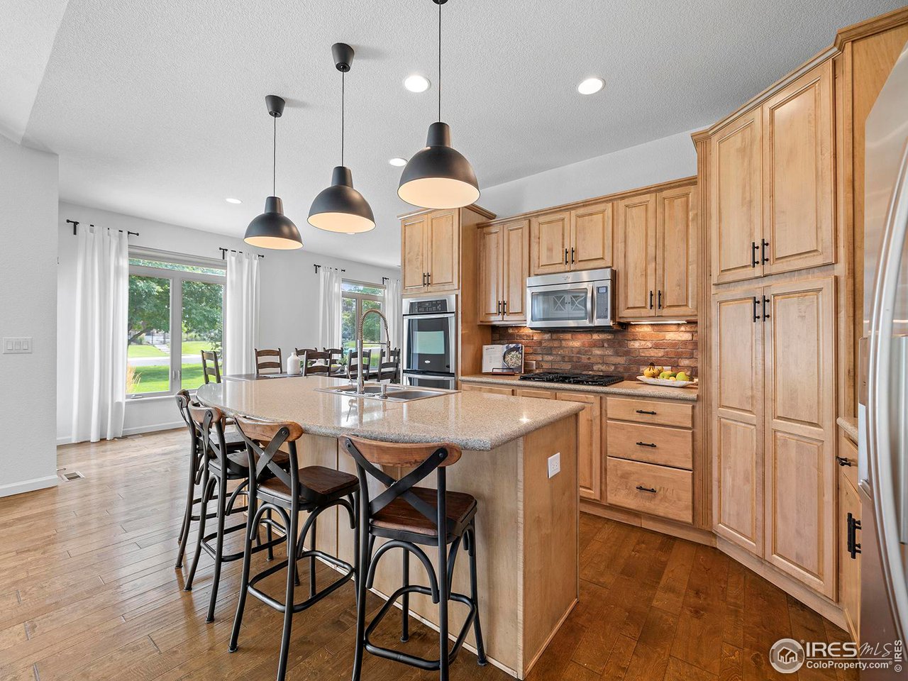 6427 Half Moon Bay Drive Windsor, CO 80550 - Photo 6 of 33 a kitchen with stainless steel appliances granite countertop a stove a refrigerator a oven a sink with a dining table and chairs